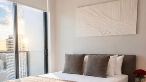 Ein modernes Schlafzimmer mit einem großen Bett, Blick auf die Stadt und einem minimalistischen Wandbild.