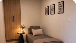 Ein Schlafzimmer mit einem Bett, einem Nachttisch, einer Lampe und einem Kleiderschrank.