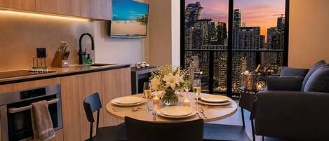 A modern kitchen with a dining area, a large window with a city view, and a cozy seating area.