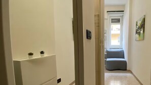 Ein Flur mit einer Tür zu einem Zimmer mit Fenster und Heizkörper.