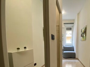 Ein Flur mit einer Tür zu einem Zimmer mit Fenster und Heizkörper.