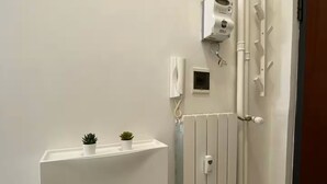 Ein Badezimmer mit weißem Heizkörper, Wandheizung, Handtuchhalter und einer kleinen Topfpflanze auf einem Regal.