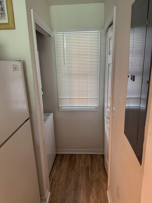 A narrow hallway with a window, a door, and a refrigerator. - Enjoyable a 2-bedroom condo with AC in vibrant Myrtle Beach, South Carolina (Myrtle Beach)