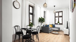 A modern living room with a dining area, a grey sofa, a small round table, and a potted plant. - Flat Near Piotrkowska Street (Łódź)