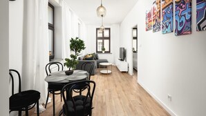 A modern living space with a dining area, a sofa, a television, and artwork on the walls. - Flat Near Piotrkowska Street (Łódź)