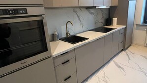 A modern kitchen with a built-in oven, a sink, and marble countertops. - Flat Near Piotrkowska Street (Łódź)