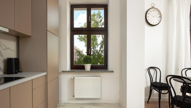 A modern kitchen with a window, a radiator, and a dining area with chairs. - Flat Near Piotrkowska Street (Łódź)