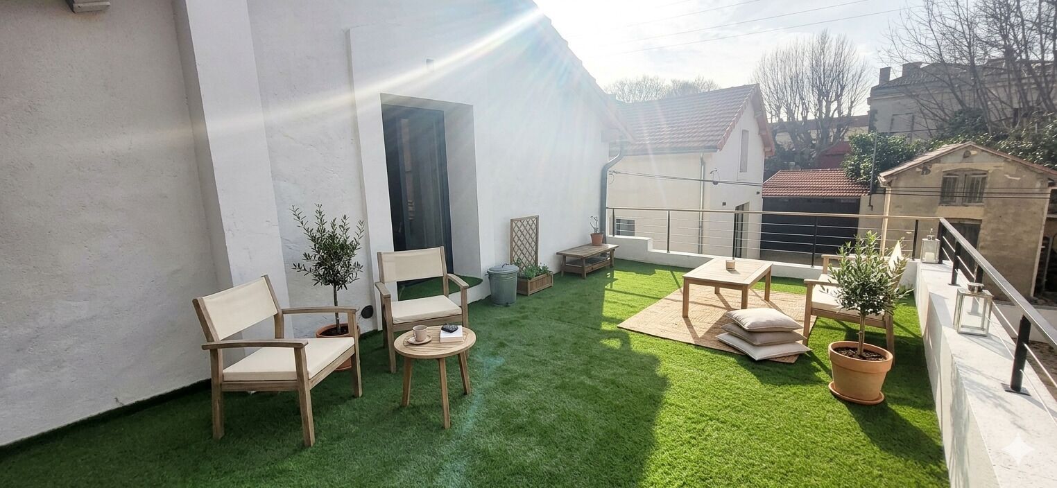 A rooftop terrace with artificial grass, seating, and potted plants.