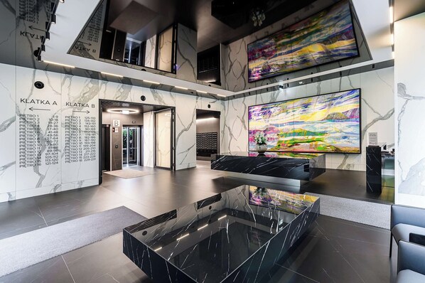 A modern lobby with a marble floor, a glass coffee table, and a large abstract painting. - Lush Home With City Views (Warsaw)