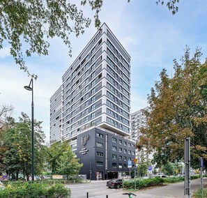 Ein modernes Hochhaus mit einer markanten Eingangspforte und einem Logo an der Fassade.