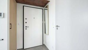 A hallway with a white door, a wooden door frame, and a black door handle. - Lush Home With City Views (Warsaw)