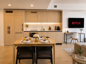 A modern kitchen with wooden cabinets, a dining table set for two, and a flat-screen TV displaying 'NETFLIX'. - 1-bedroom hotel in lovely Miami with cool AC comfort (Miami)