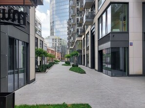 Eine moderne Stadtstraße mit Hochhäusern, einem gepflasterten Bürgersteig und kleinen Grünflächen.