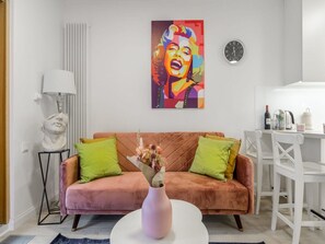 Ein Wohnzimmer mit einer Couch, einem Couchtisch, einer Lampe, einer Skulptur, einem Gemälde und einer Uhr.