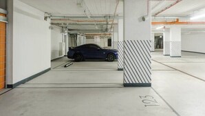 A parking garage with a blue car parked in a spot marked 103. - City Apartment With Balcony (Warsaw)