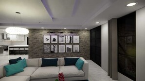 A modern living room with a sofa, artwork on the wall, and a kitchen in the background. - Charming 5-bedroom house with AC in Tower Isle (Tower Isle)