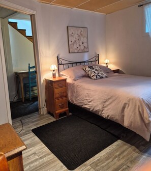Ein Schlafzimmer mit Bett, Nachttischen, einem Schminktisch, einem Teppich und einem Bild an der Wand.