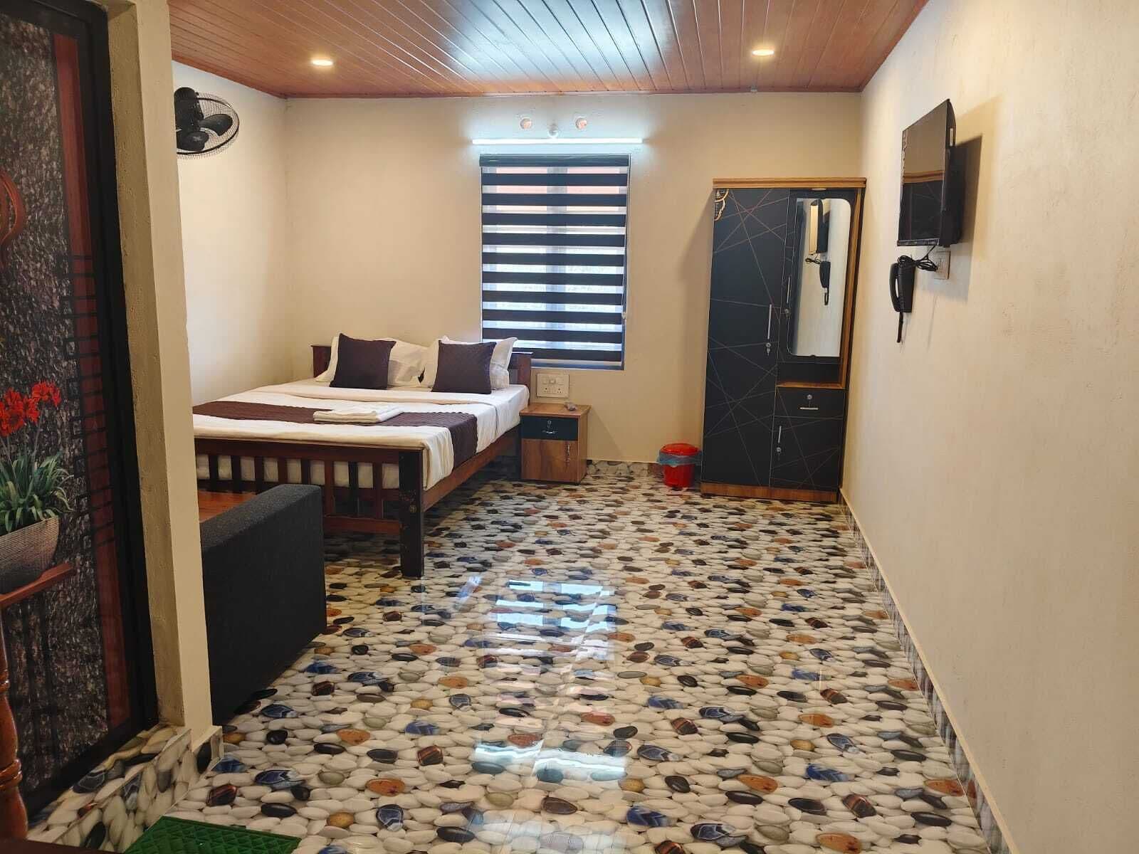 A bedroom with a bed, bedside table, and a window with blinds.