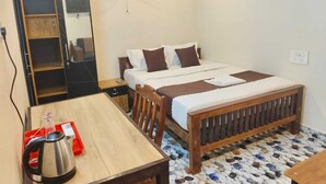 A bedroom with a bed, a wooden table, a kettle, and a wardrobe.