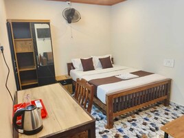 A bedroom with a bed, a wooden table, a kettle, and a wardrobe.