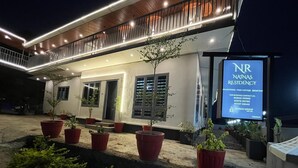A modern building with a sign for Natinas Residency, featuring a balcony with railings and potted plants.