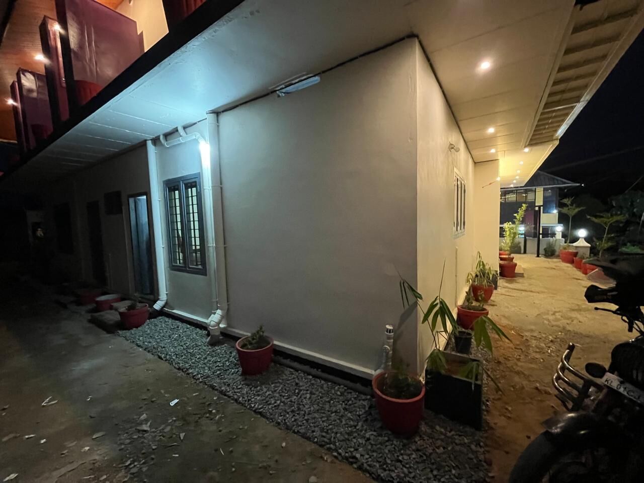 A building with a white exterior, a door, and potted plants along the side.