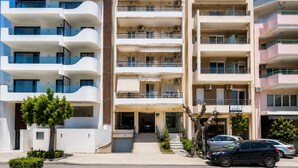 A multi-story residential building with balconies, a gated entrance, and a parking area with cars. - Deluxe Apartment With Balcony and Views (Rethymno)