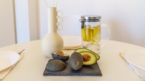 A table with a white vase, a glass pitcher, and avocados. - Deluxe Apartment With Balcony and Views (Rethymno)