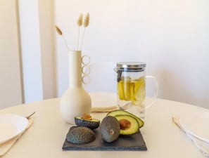 Ein Tisch mit einer weißen Vase, einem Glasbehälter und Avocados.