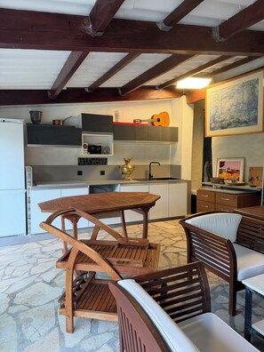 Una cucina rustica con travi in legno, pavimento in pietra e zona pranzo con mobili in legno.