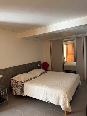 Una camera da letto con un letto, un comodino, una sedia rossa e un armadio.