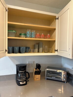 A kitchen with a coffee maker, toaster, and a knife block on the counter. - Sunny Cove Retreat: Walk to Beach, Dining & Marina (Deerfield Beach)