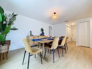 Ein Essbereich mit einem Holztisch, sechs Stühlen und einer Deckenleuchte.