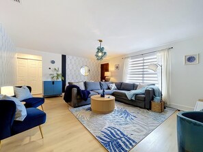 Ein modernes Wohnzimmer mit einer Sofagarnitur, einem Couchtisch und einem gemusterten Teppich.