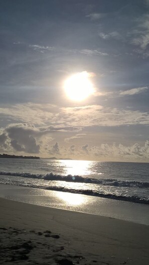 A beach with the sun setting over the ocean, creating a calm atmosphere. - Villa Le Diamant (le diamant)