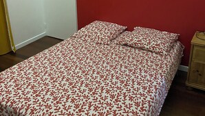 Ein Schlafzimmer mit einem Bett, einer Tür, einem Gemälde und einem Nachttisch.