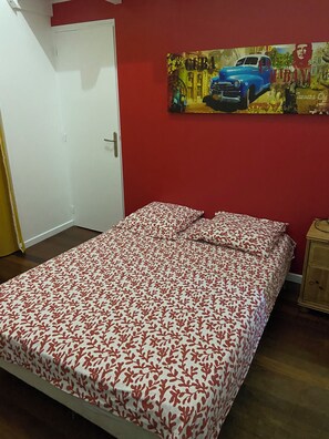 A bedroom with a bed, a door, a painting, and a nightstand. - Villa Le Diamant (le diamant)