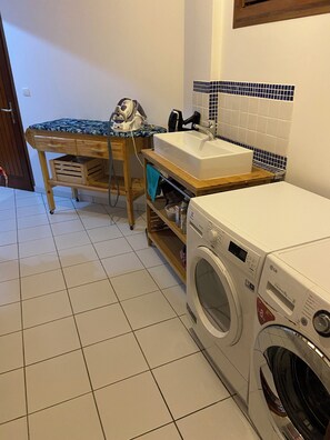 A compact laundry area with a washing machine, a sink, and a drying rack. - Villa Le Diamant (le diamant)