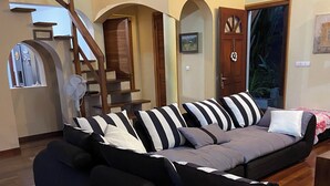 Ein stilvolles Wohnzimmer mit einem Ecksofa, Holzboden und einer Treppe.