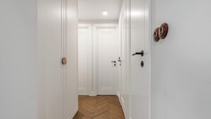 A hallway with white walls and wooden flooring, leading to two closed doors. - Family Stay in Warsaw (Warsaw)