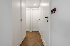 A hallway with white walls and wooden flooring, leading to two closed doors. - Family Stay in Warsaw (Warsaw)