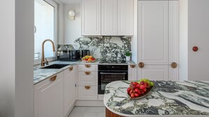 A modern kitchen with white cabinetry, a marble countertop, and a built-in oven. - Family Stay in Warsaw (Warsaw)