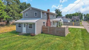 A two-story house with a fenced yard, a chimney, and a small porch.