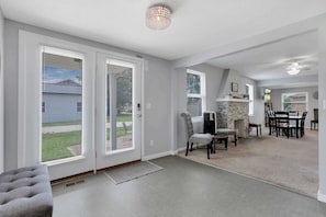 A spacious living area with a fireplace, a dining table with chairs, and a grey sofa.