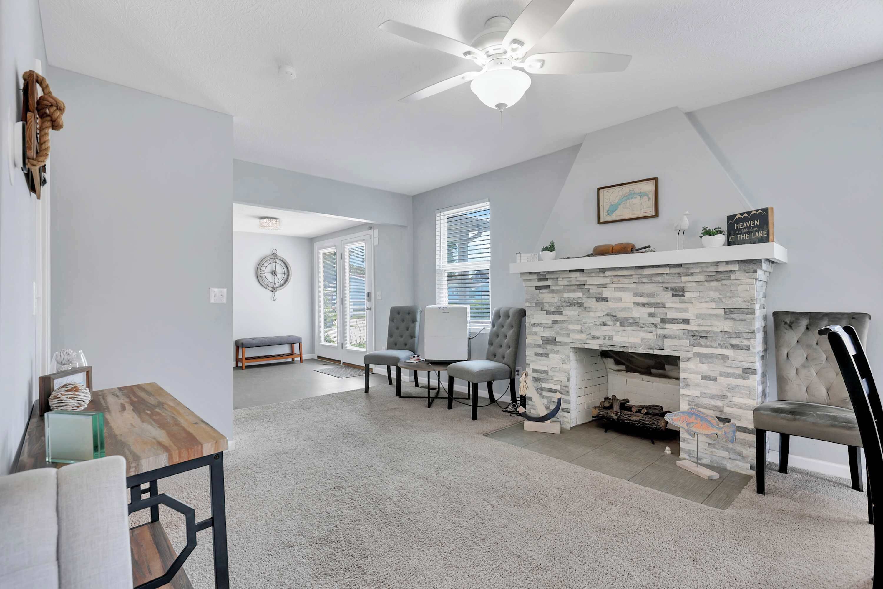 A living room with a stone fireplace, a ceiling fan, and a dining area with a wooden table and chairs.
