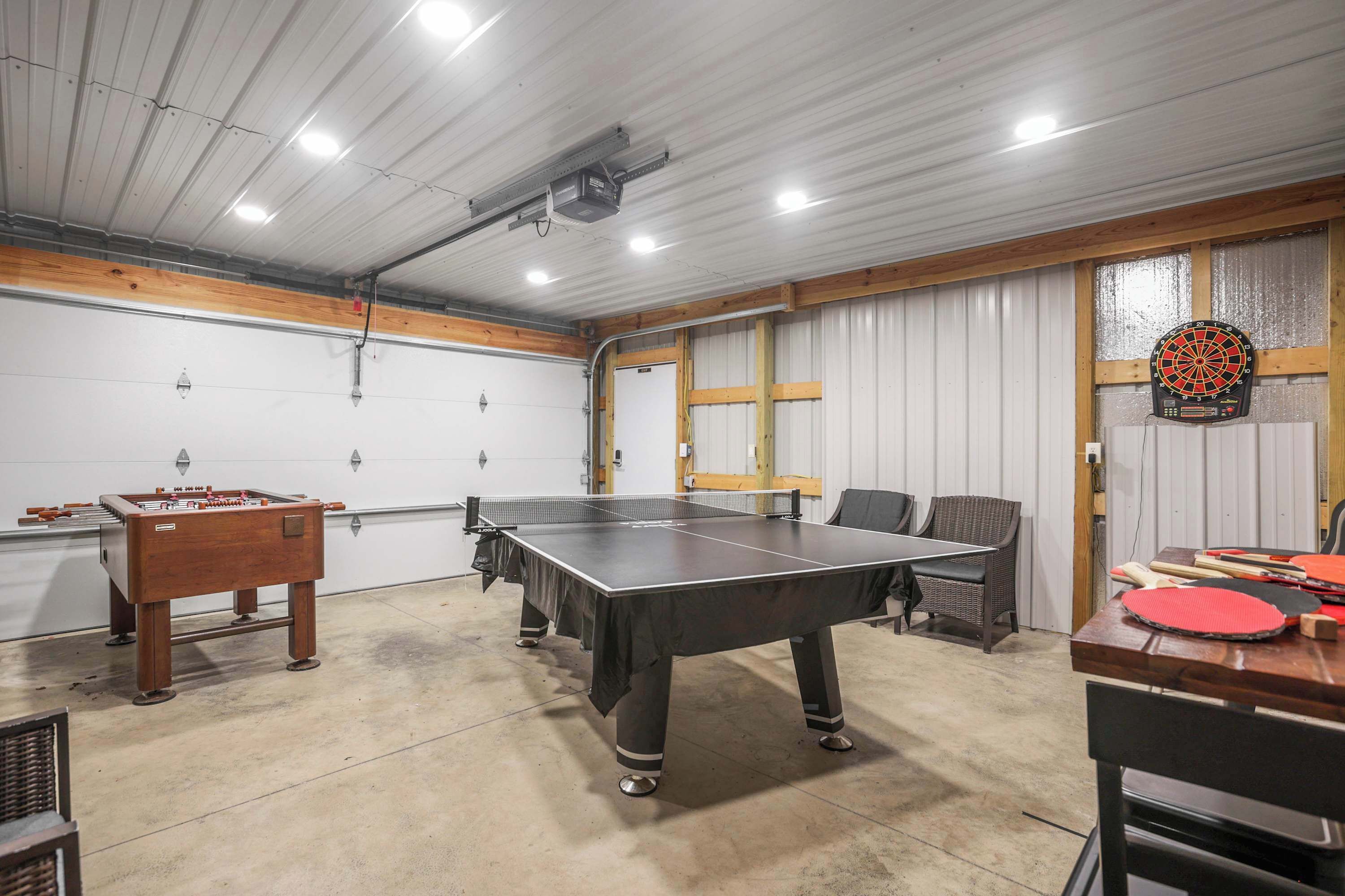 Une salle de loisirs équipée d’un baby-foot, d’une table de ping-pong, d’un jeu de fléchettes et d’un autre baby-foot avec un plateau en bois.