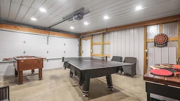 Une salle de loisirs équipée d’un baby-foot, d’une table de ping-pong, d’un jeu de fléchettes et d’un autre baby-foot avec un plateau en bois.