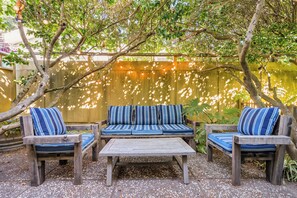 Un espacio al aire libre con mesa de madera y dos sofás con cojines a rayas.