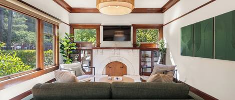 A living room with a fireplace, a sofa, and a television mounted above the fireplace.