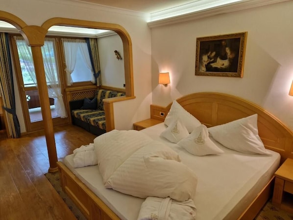 A hotel room with a wooden bed, a nightstand, a wall-mounted lamp, and a painting. - Residence Ciastel (Oltretorrente)
